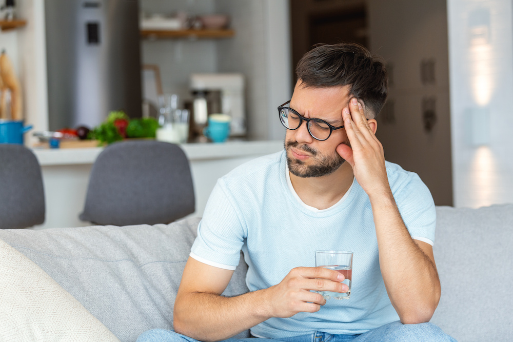 Man sitting on couch with headache 